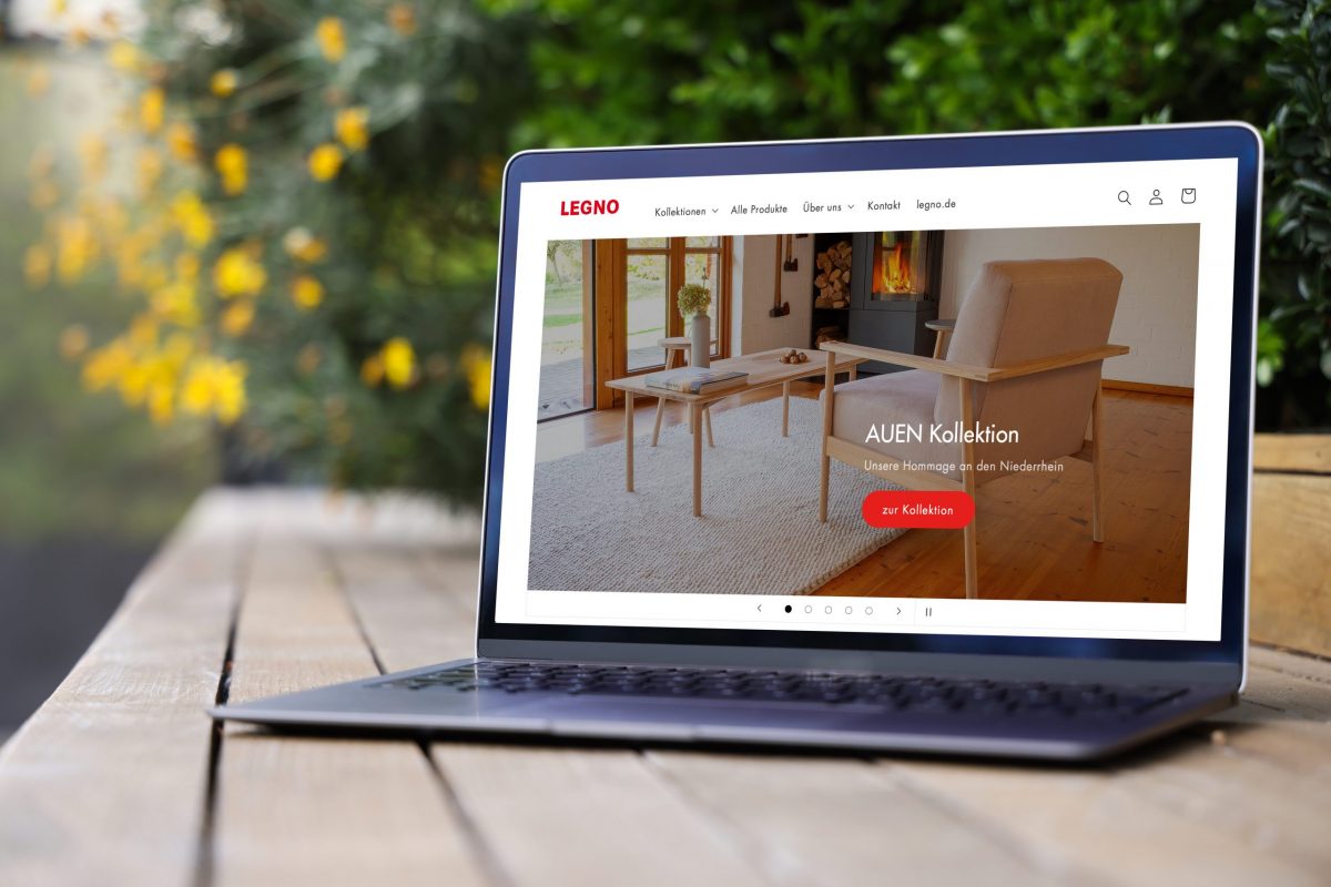 Laptop im Außenbereich mit geöffnetem Browser auf dem die Startseite des Legno Onlineshops mit der AUEN Kollektion zu sehen ist.