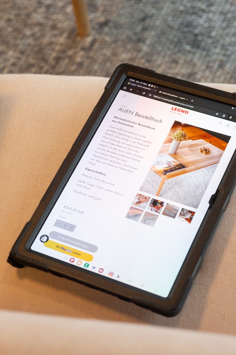 Tablet auf einem Sessel mit geöffnetem Browser, auf dem der Shop von Legno Atelier geöffnet ist.